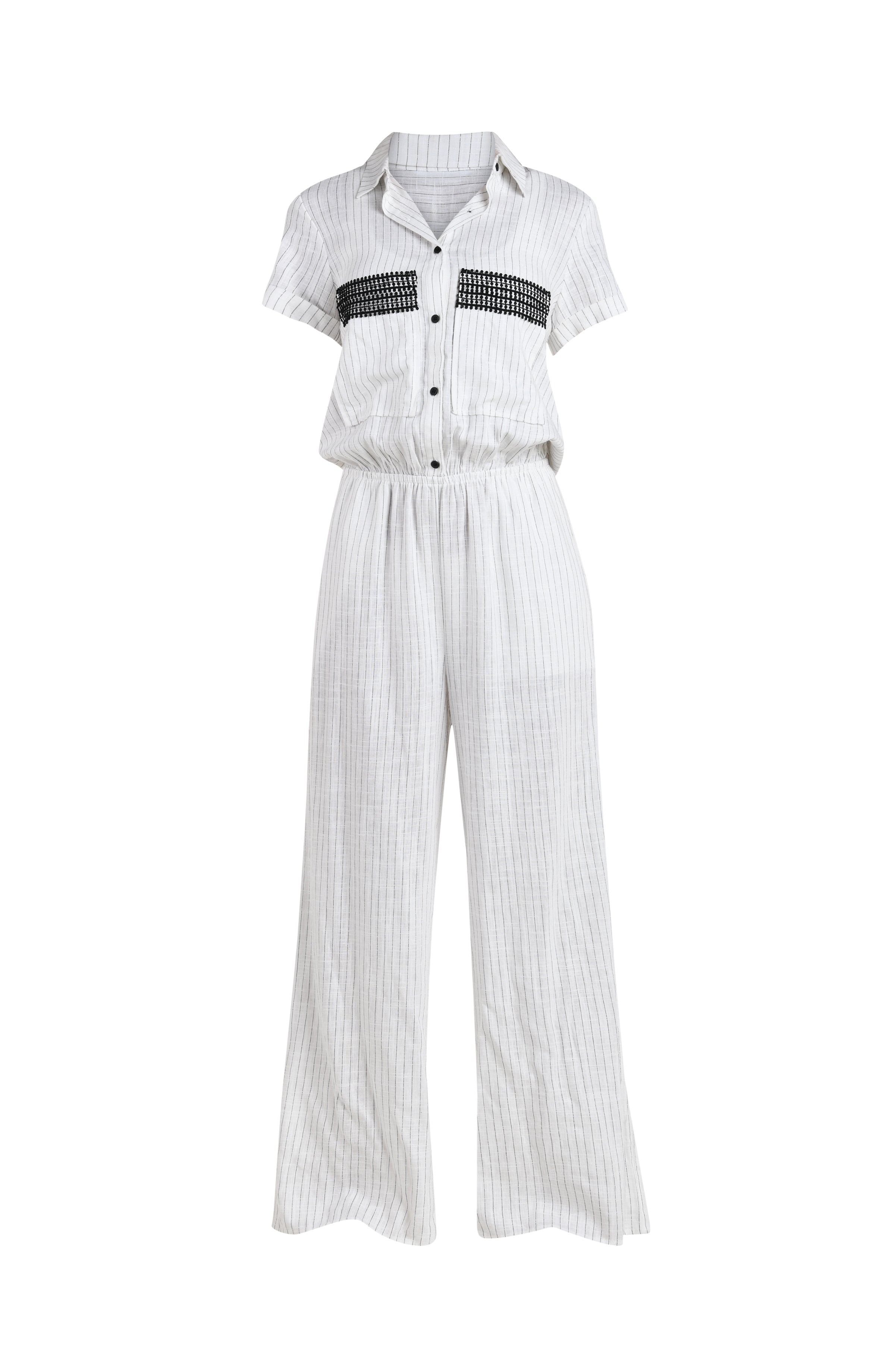 Floating image of a pant jumpsuit in a button up collared front with wide pockets adorned with crochet trim, short sleeves, and pant pockets. Featuring a cream colored linen print. 
