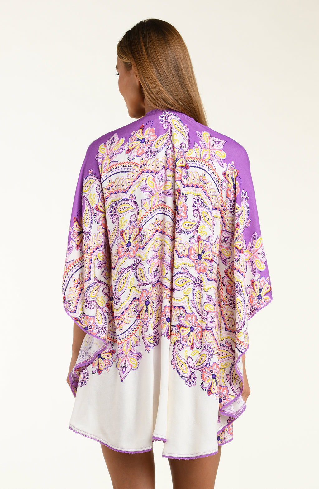 Woman wearing a purple multicolored floral kimono cover up over a white background