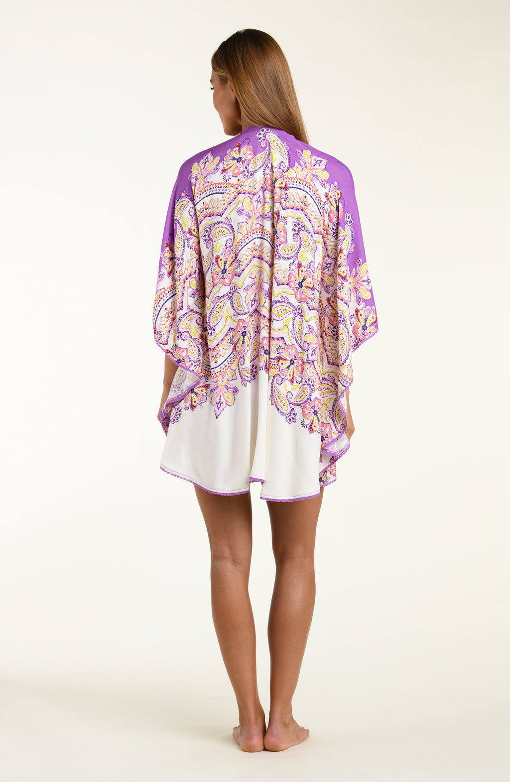 Woman wearing a purple multicolored floral kimono cover up over a white background