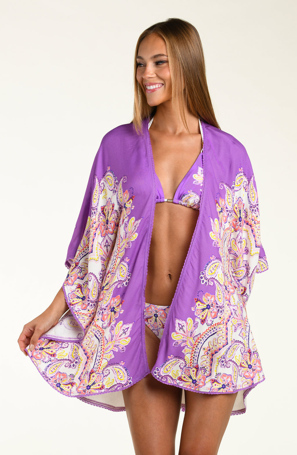 Woman wearing a purple multicolored floral kimono cover up over a white background