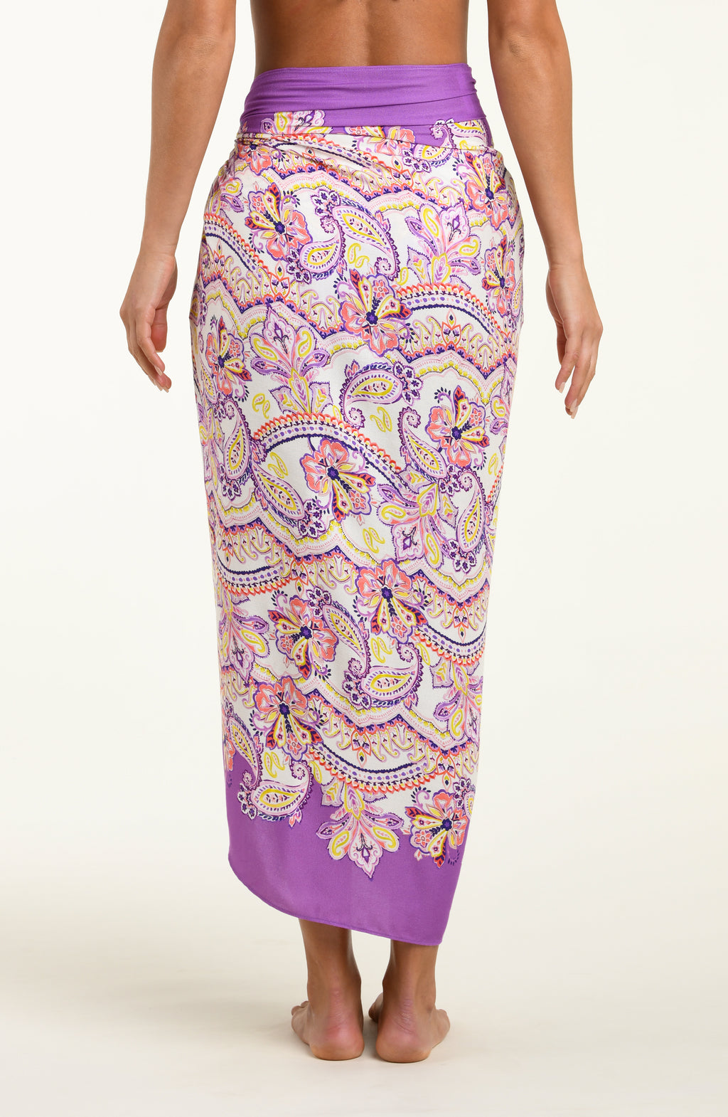 Person wearing a multicolored purple pareo wrap against a white background