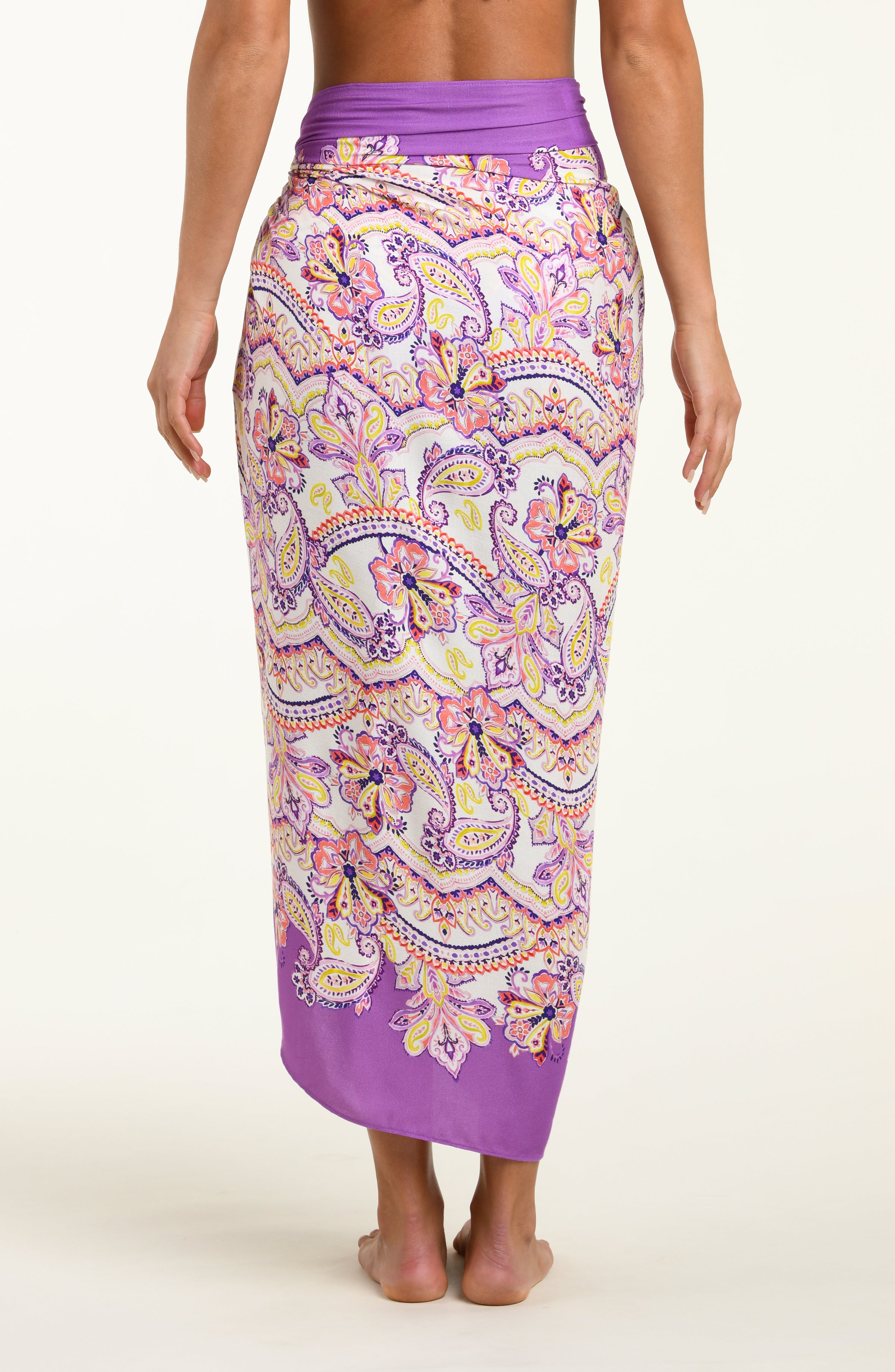Person wearing a multicolored purple pareo wrap against a white background