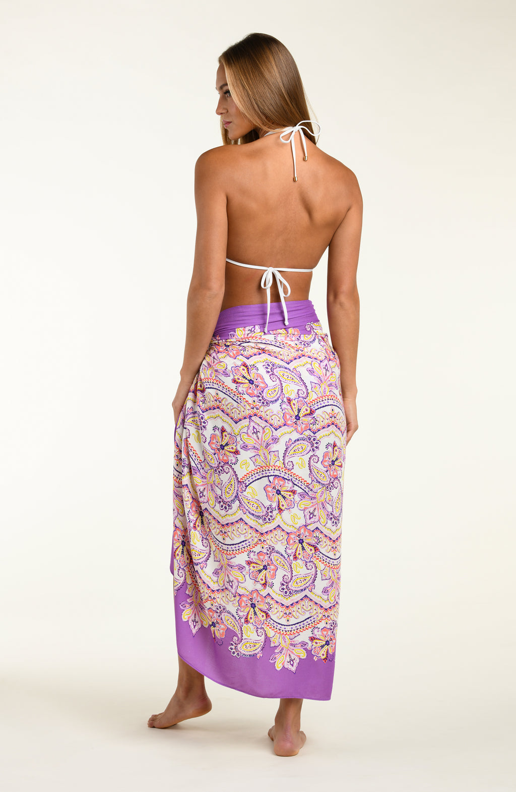Person wearing a multicolored purple bikini top and matching pareo wrap against a white background