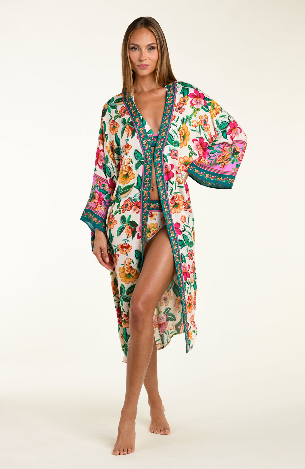 Woman wearing a multicolored floral bikini top and bottoms, with matching long kimono cover-up on a white background