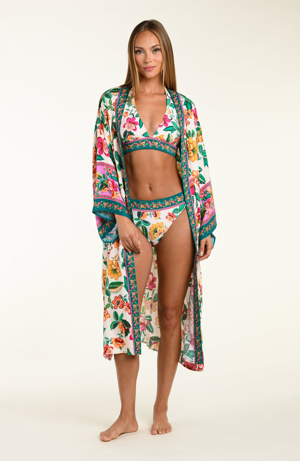 Woman wearing a multicolored floral bikini top and bottoms, with matching cover-up on a white background