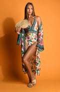 Woman wearing a multicolored floral one piece with matching cover-up on an orange background