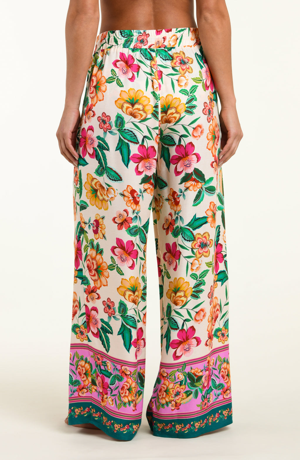 Multicolored floral-patterned beach pants worn by a person on a white background