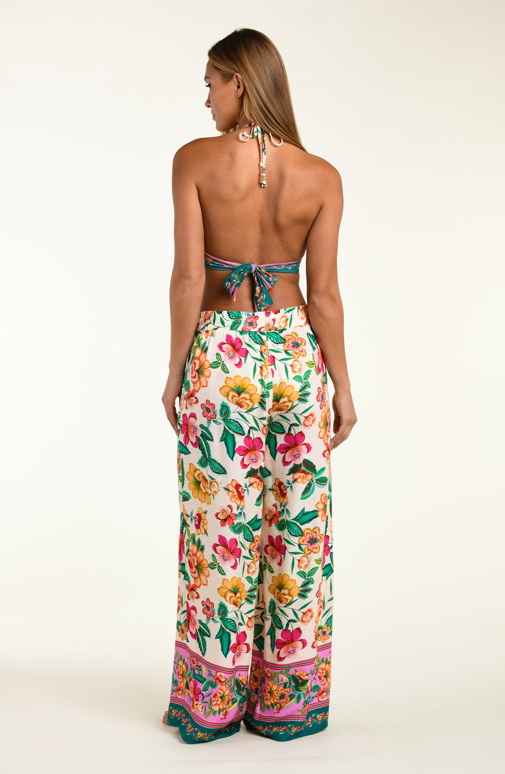 Multicolored floral-patterned bikini top and matching beach pants worn by a person on a white background