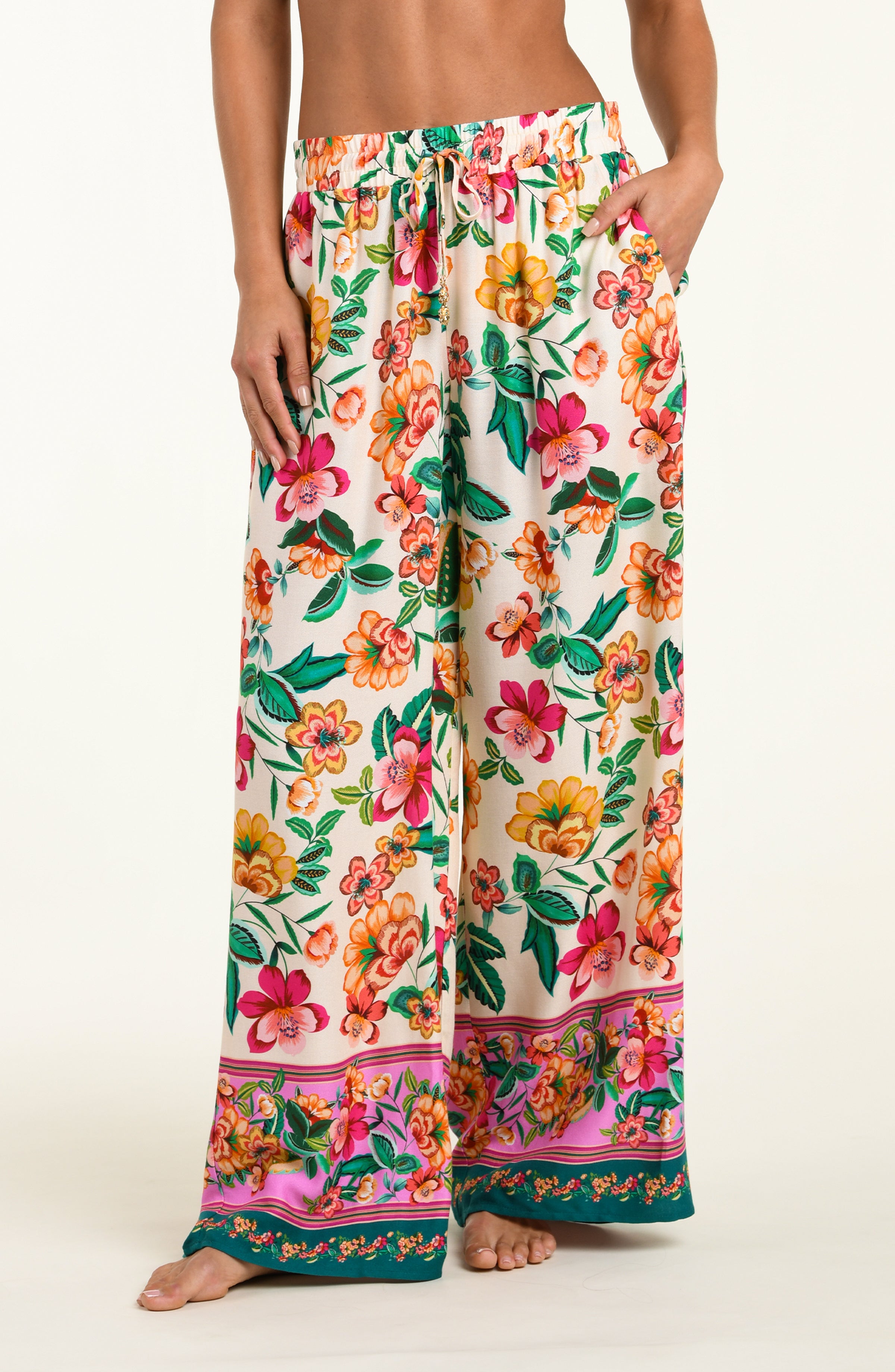Multicolored floral-patterned beach pants worn by a person on a white background