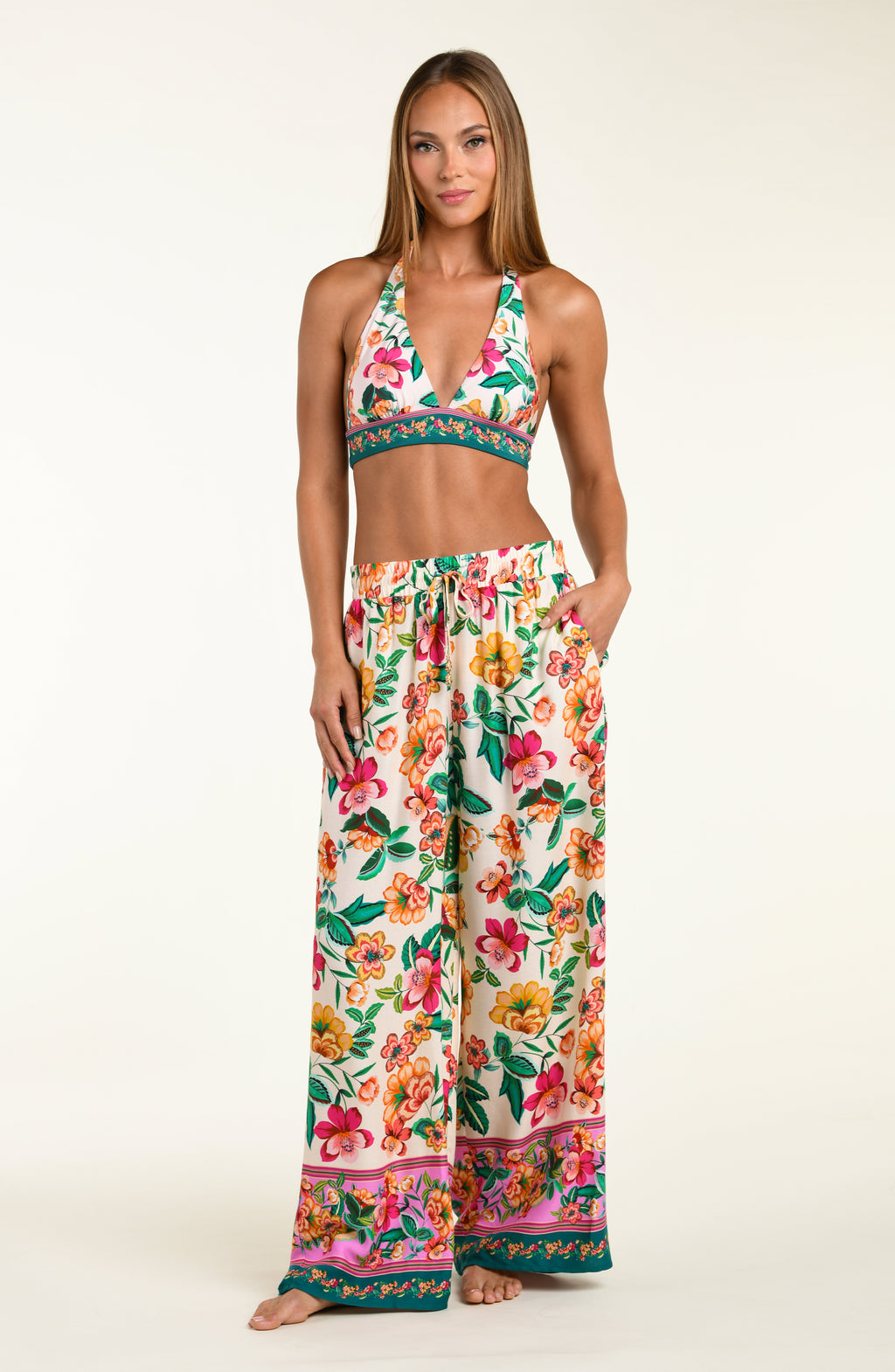 Multicolored floral-patterned bikini top and matching beach pants worn by a person on a white background
