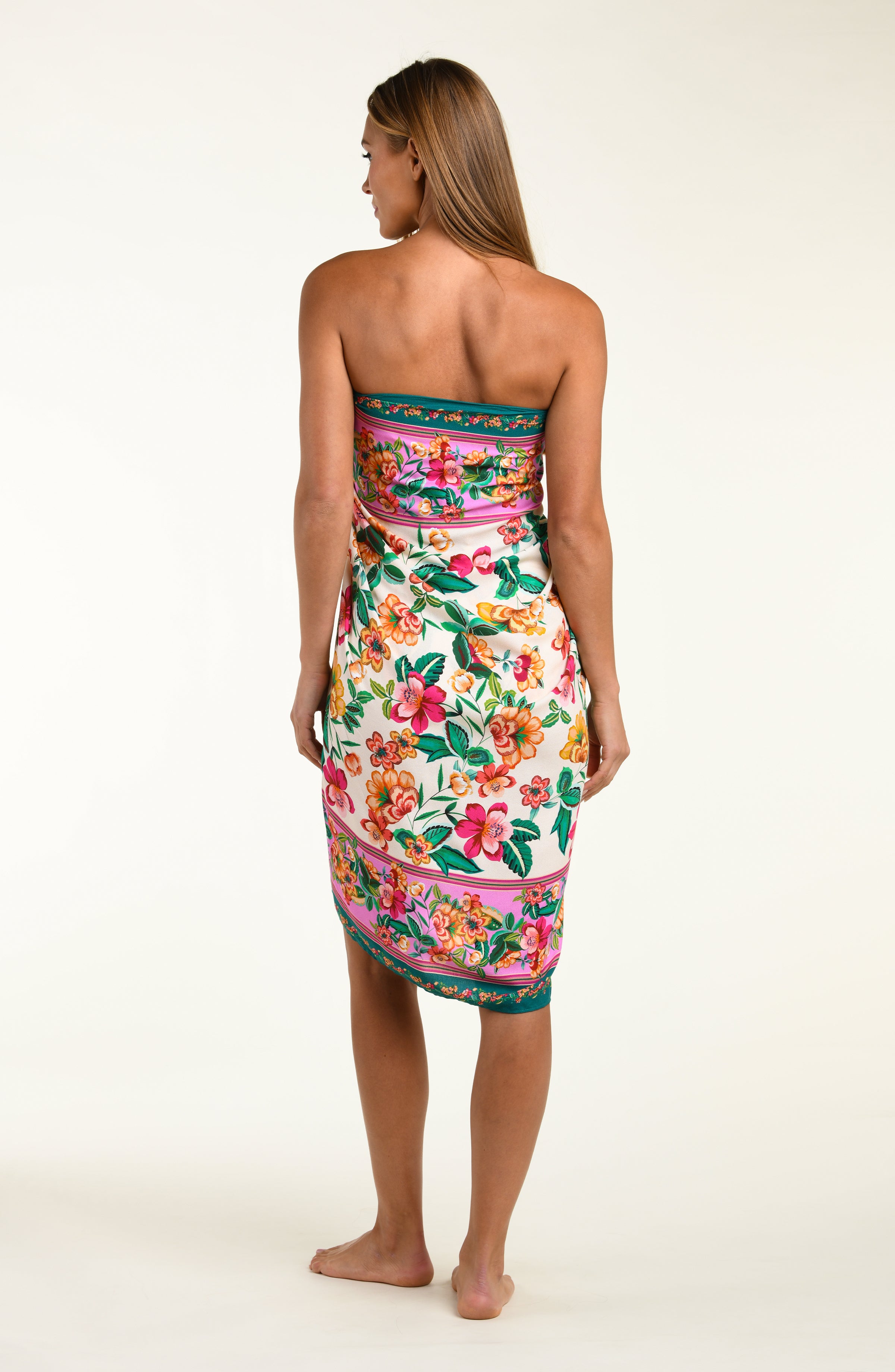 Woman wearing a floral patterned  pareo cover up worn by a person on a white background