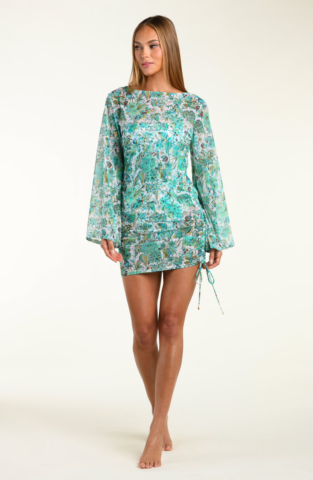Woman wearing a turquoise floral tunic cover up with bell sleeves on a white background