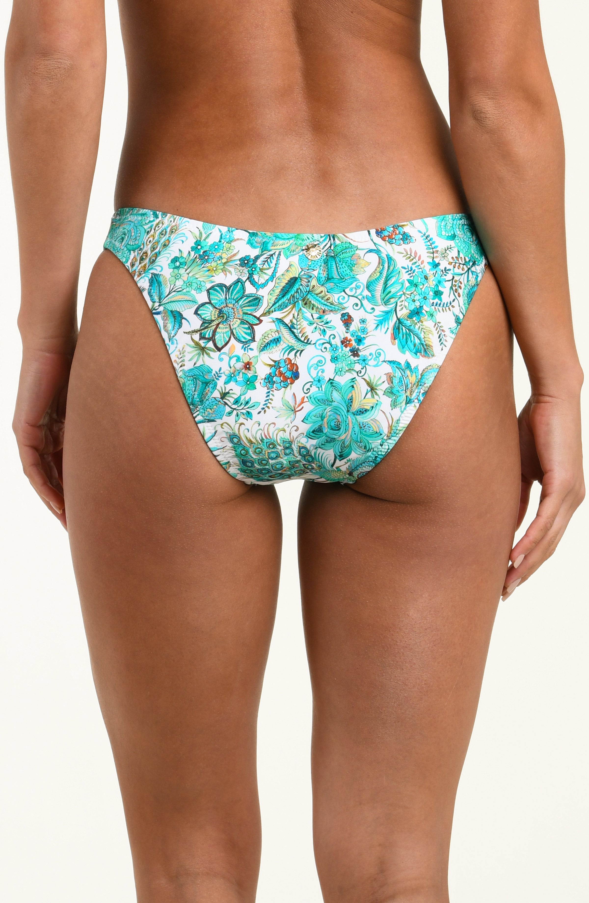 Woman wearing a floral turquoise bikini bottom against a white background