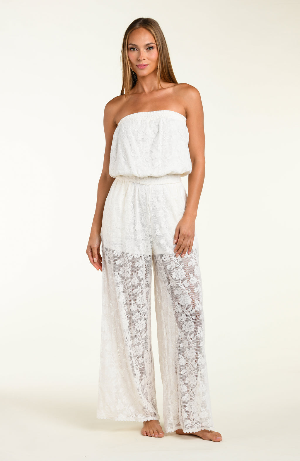 Woman wearing a white lace jumpsuit cover up against a white background.