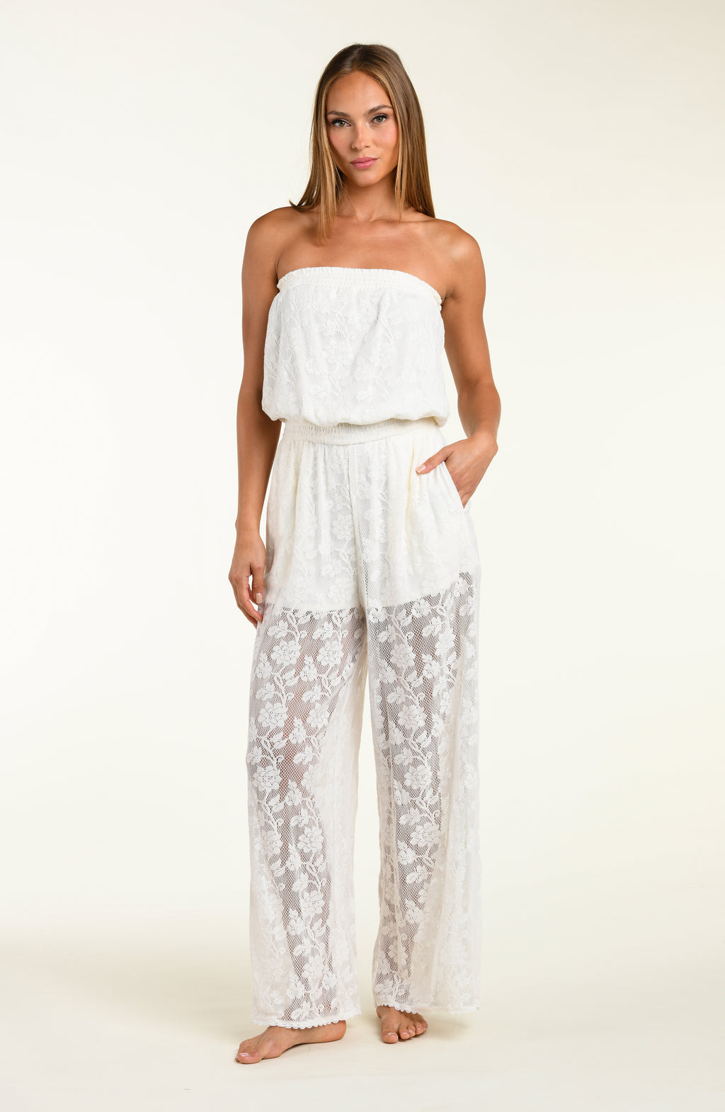 Woman wearing a white lace jumpsuit cover up against a white background.