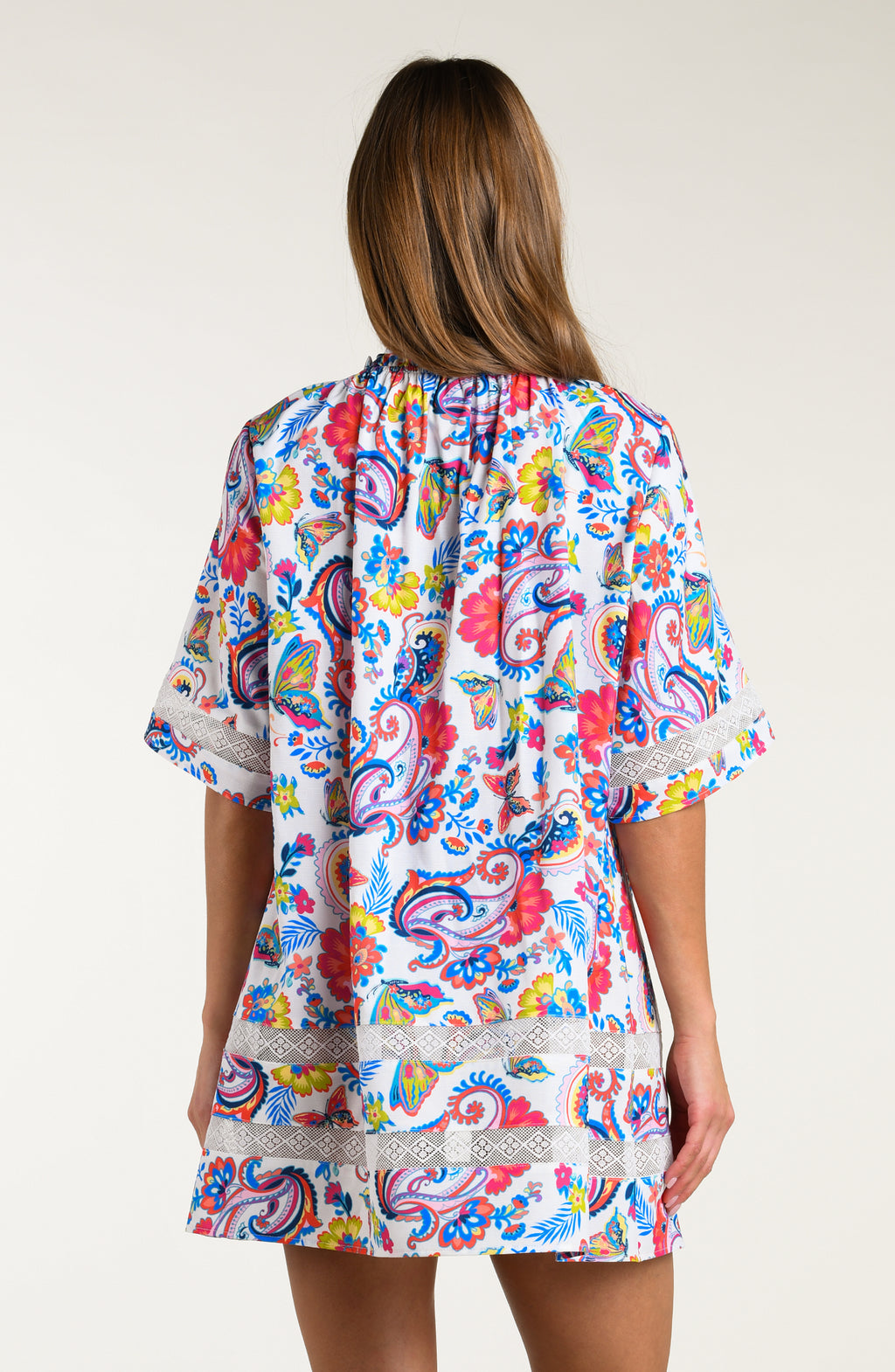 Woman wearing a multicolored tunic cover up against a white background.