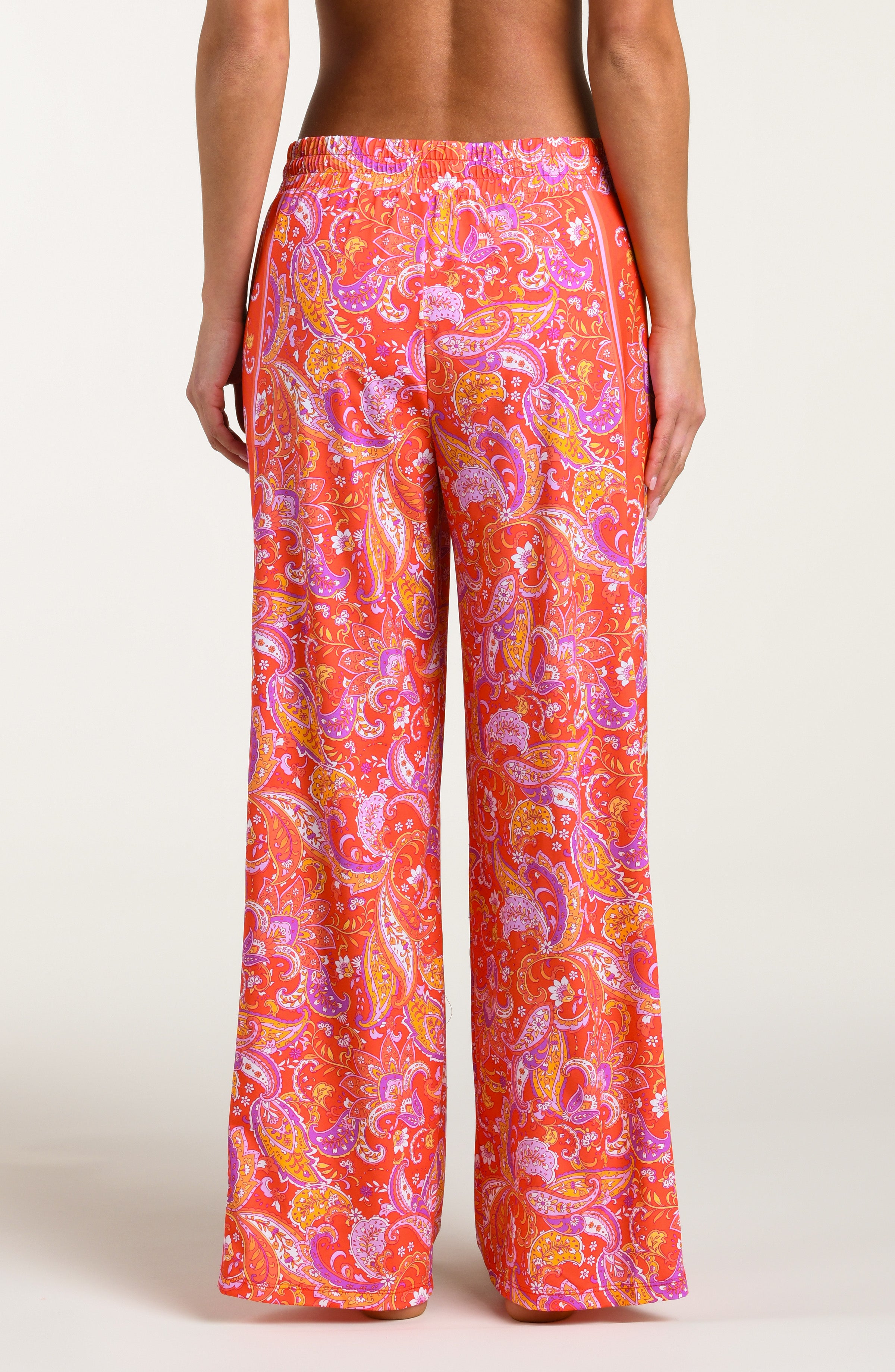 Pink and orange multicolored patterned pants worn by a person on a white background.
