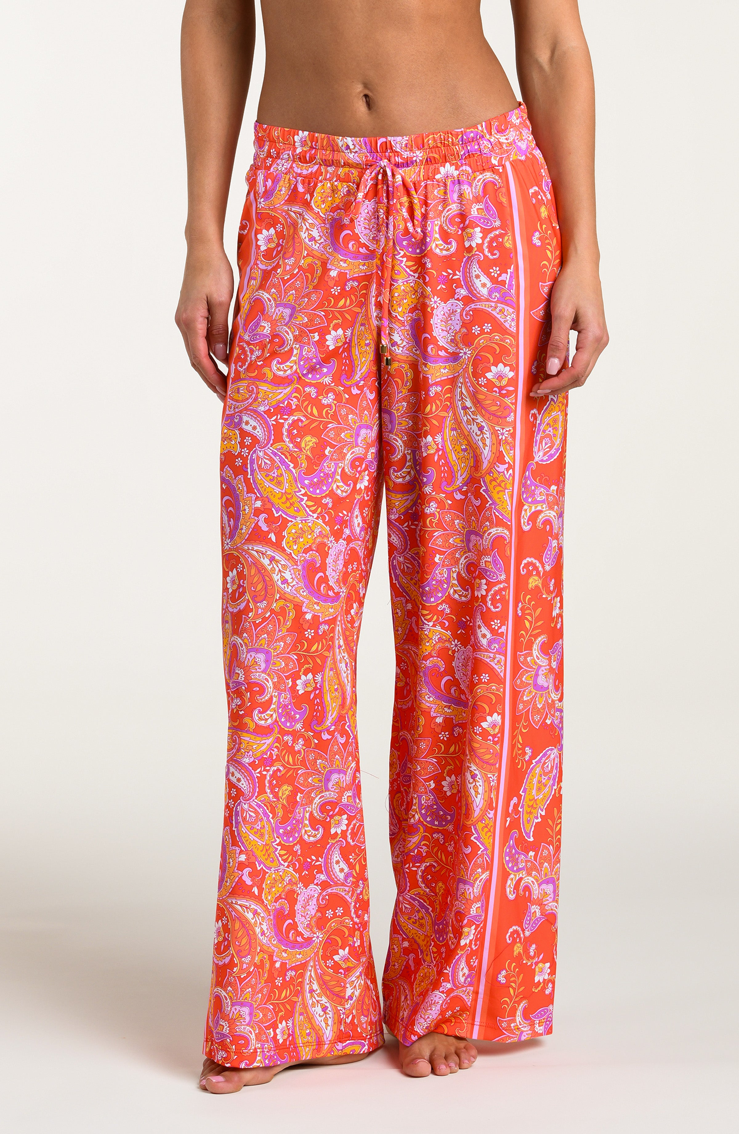 Pink and orange multicolored patterned pants worn by a person on a white background.