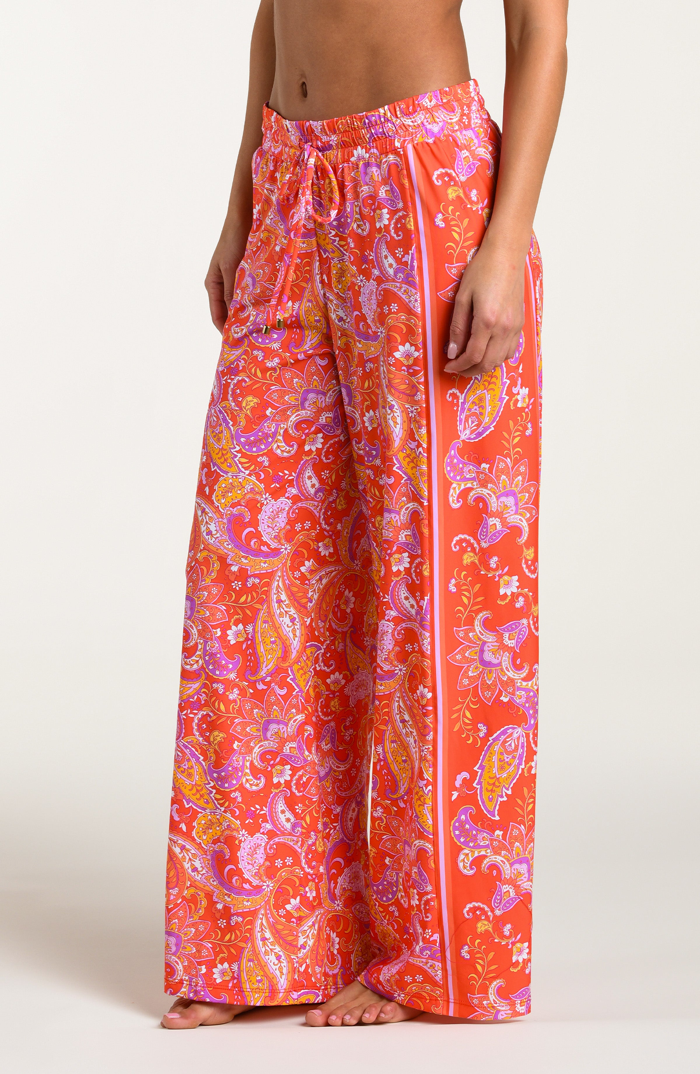 Pink and orange multicolored patterned pants worn by a person on a white background.