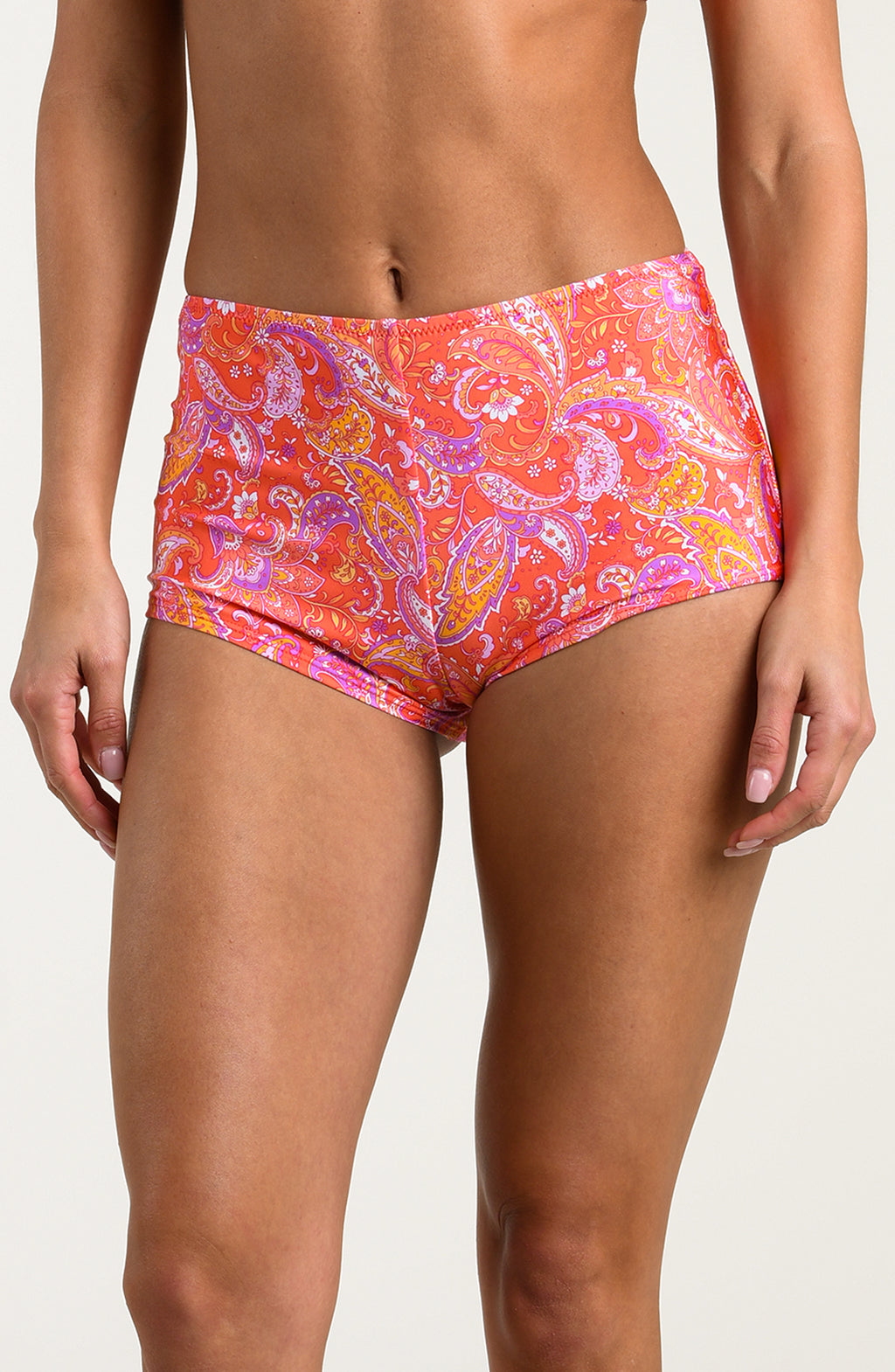 Person wearing pink and orange multicolored swim shorts on a white background