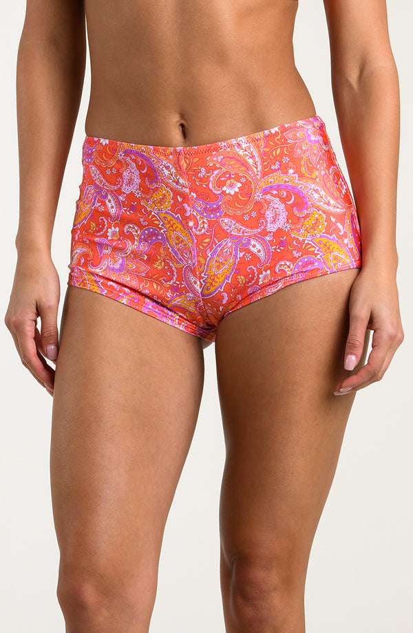 Person wearing pink and orange multicolored swim shorts on a white background