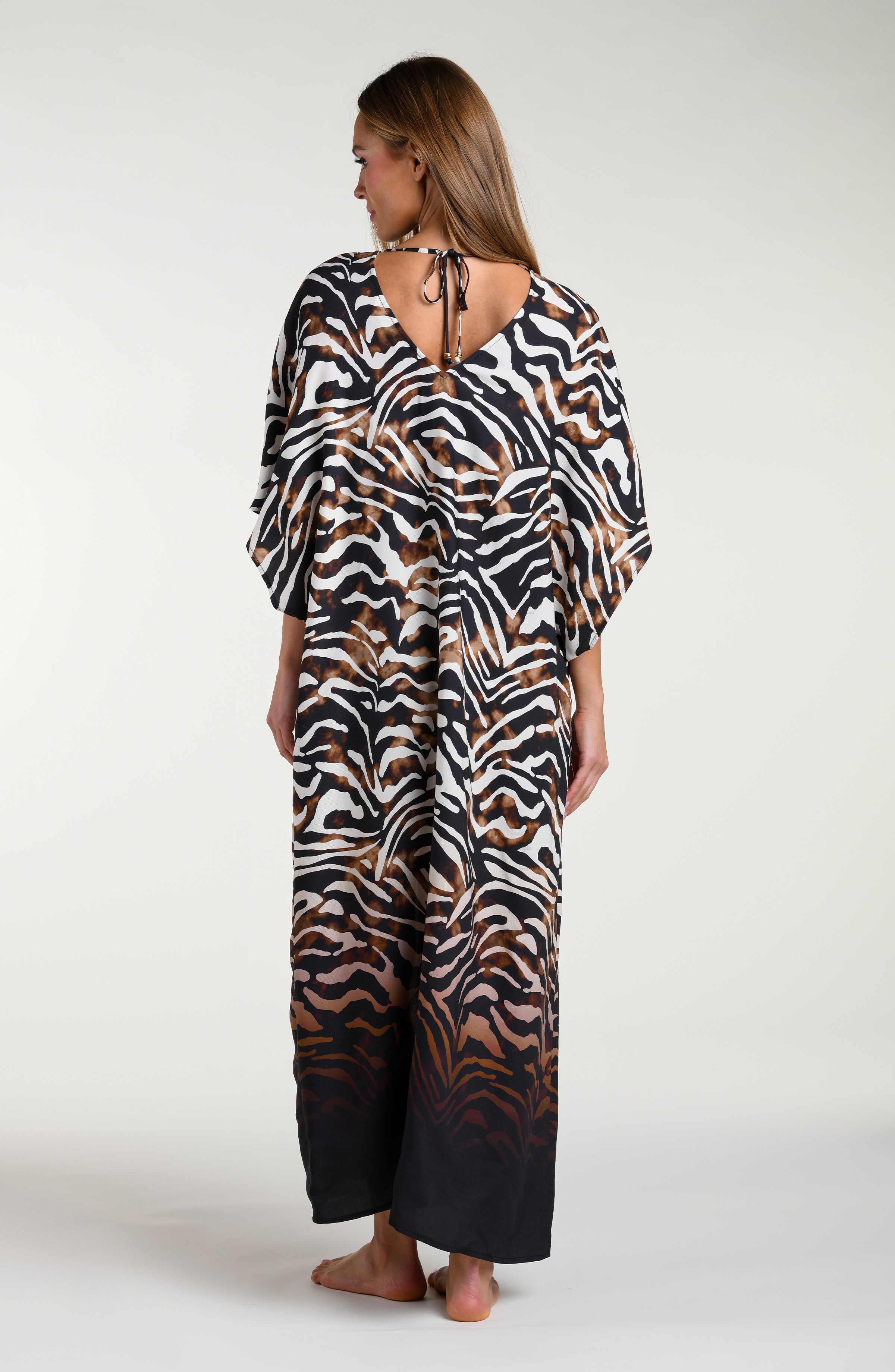 Woman wearing a zebra print caftan cover up against a white background