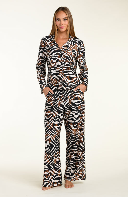 Woman wearing an animal printed shirt and pant matching pajama set on a white background
