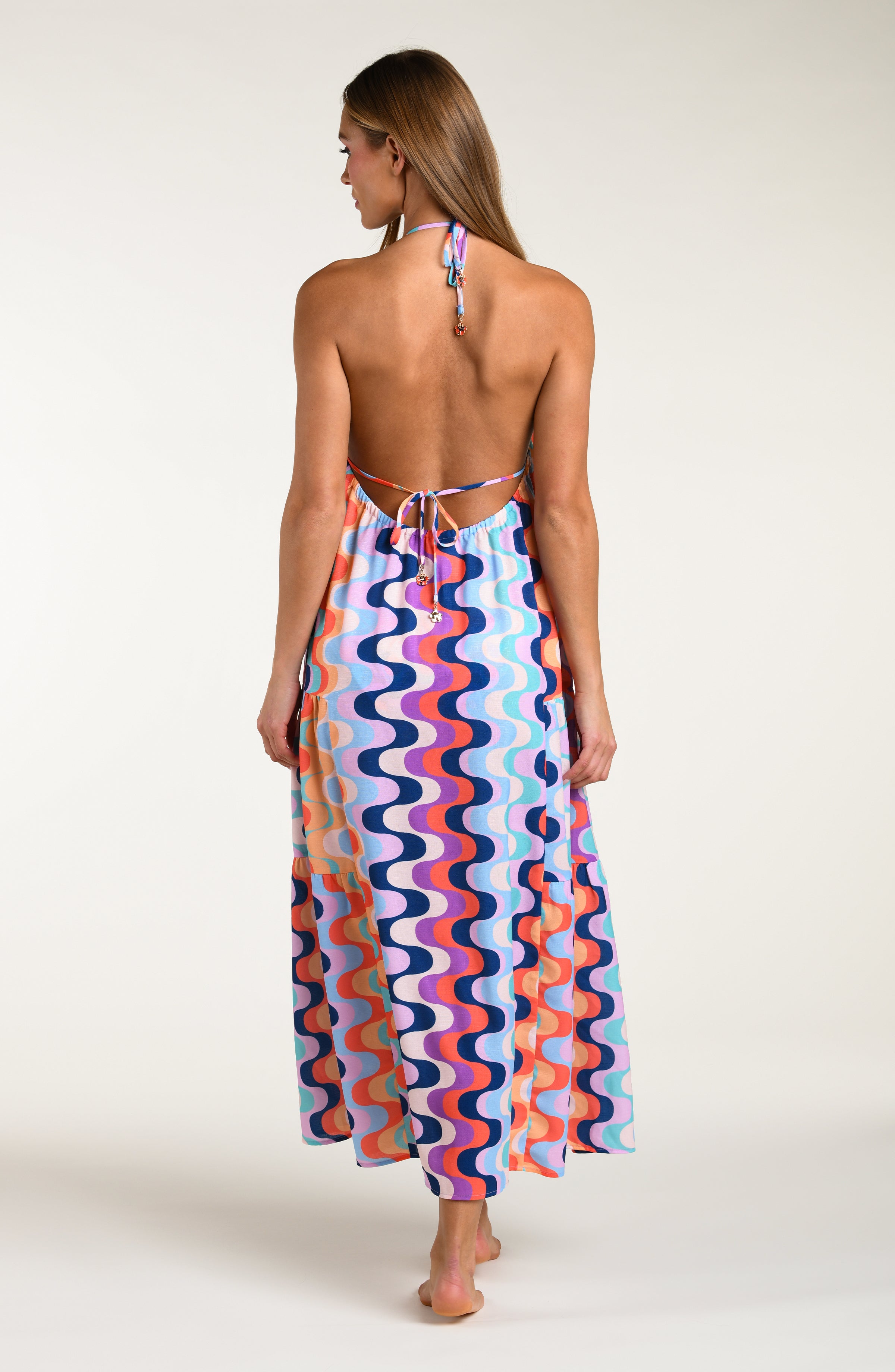 Woman wearing a colorful patterned maxi dress on a white background