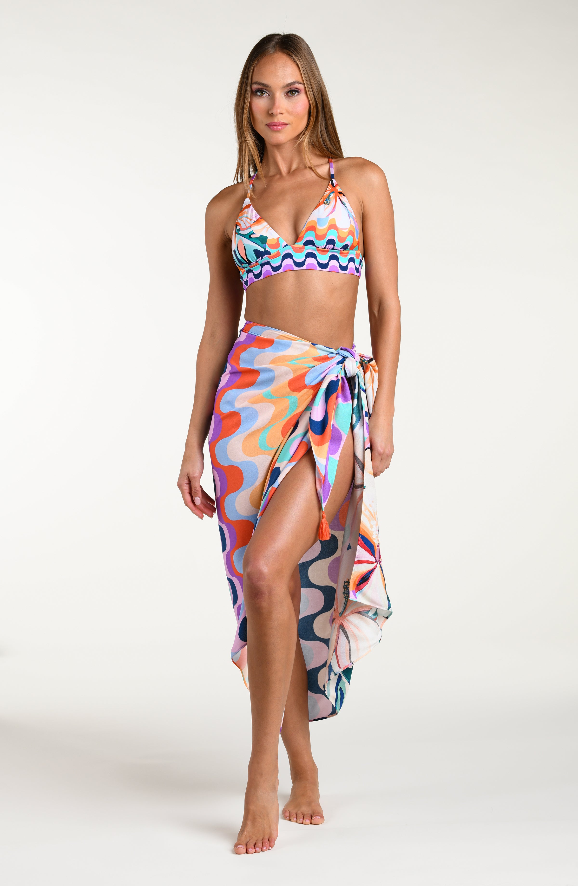 Woman wearing a multicolored patterned bikini top and matching pareo wrap on a white background