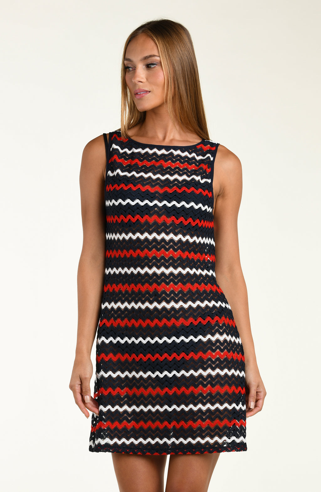 Woman wearing a sleeveless dress with red, white, and black zigzag pattern on a plain background