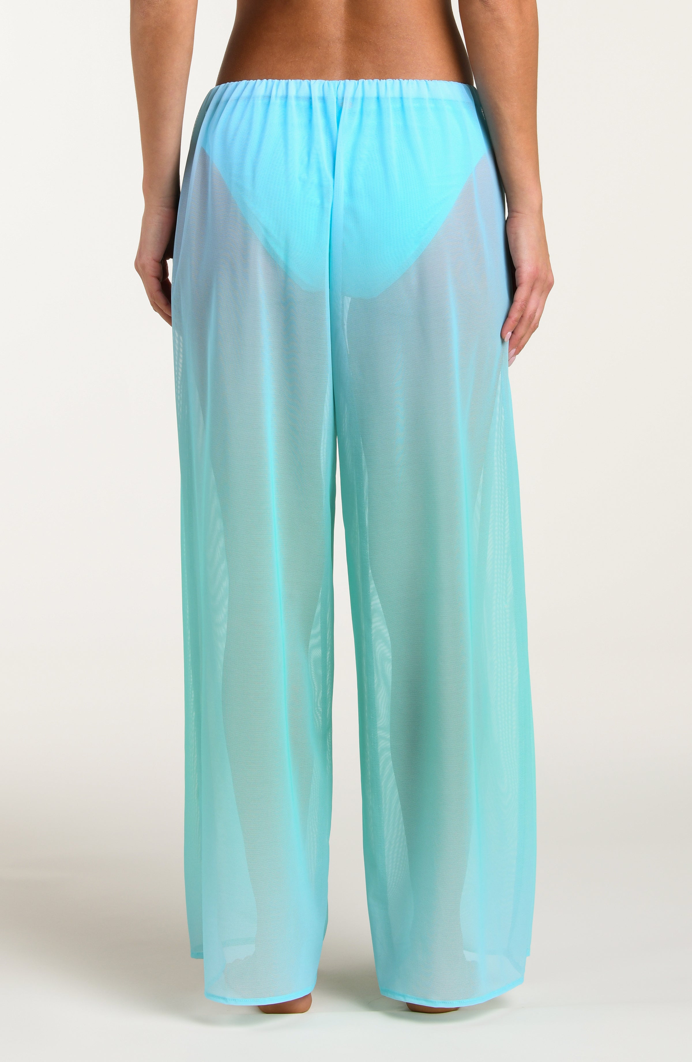 Turquoise colored sheer pants worn by a person against a white background
