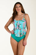 Woman wearing a colorful floral tankini top and teal high-waisted bottoms on a white background
