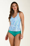 Woman wearing a patterned tankini top and green high-waisted bottoms on a white background