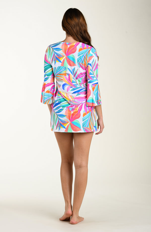 Full body back image of model wearing a multicolored (mostly pink) tropical printed cover-up dress featuring a relaxed, flowy fit with three-quarter sleeves, a tie-front neckline, and pockets.