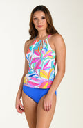 Front image of model wearing a multicolored pink tropical printed tankini top featuring adjustable straps, removable cups, and underwire. This is paired with periwinkle (blue) colored bikini bottoms.