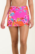 Front image of model wearing a multicolored pink floral printed swim skort featuring a sleek, figure-flattering fit with built-in shorts, pockets, and full rear coverage.
