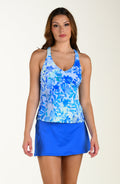 Woman wearing a blue floral tankini and periwinkle skirt on a beige background