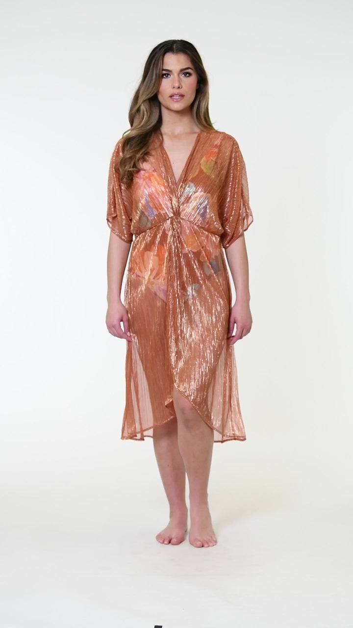 Model is wearing a shimmering orange and pink short sleeve midi dress cover up.