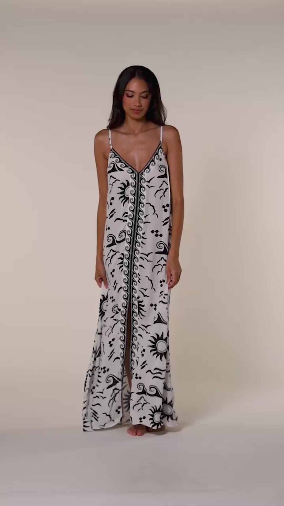 Video of a woman wearing a black and white patterned maxi dress against a white background