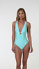 Model is wearing a solid pale, greenish-blue (seaglass) colored plunge one piece swimsuit.