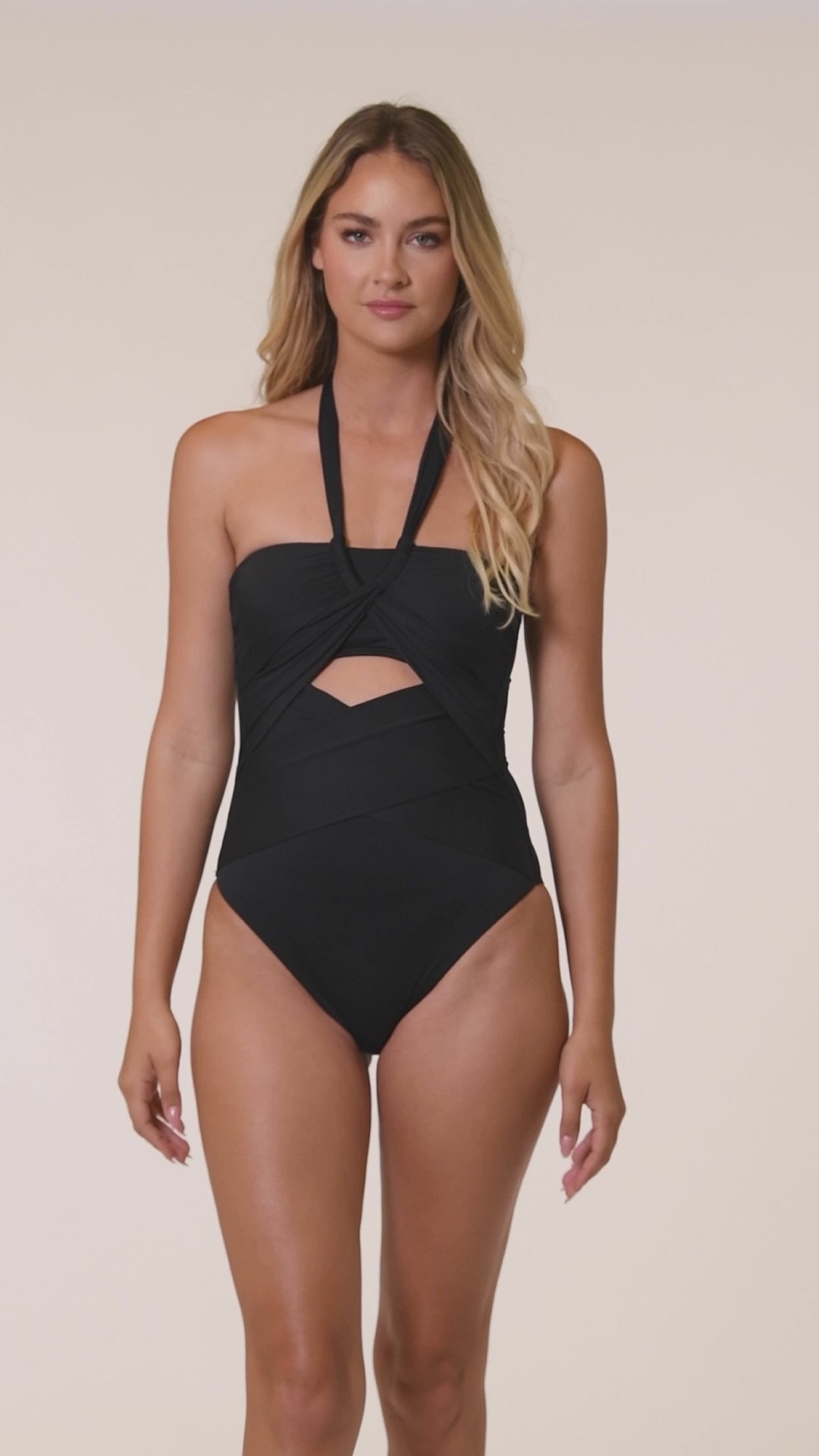 Model is wearing a solid black halter one piece swimsuit.