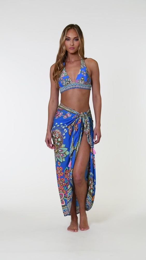 
                  
                    Load and play video in Gallery viewer, Model is wearing a pink, orange, teal, and green multicolored floral patterned pareo swimsuit cover up set against an indigo blue background.
                  
                