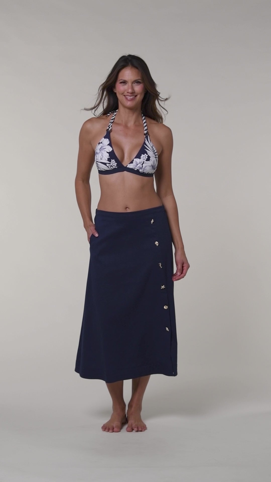 Video of a woman wearing a navy cover up skirt against a white background.