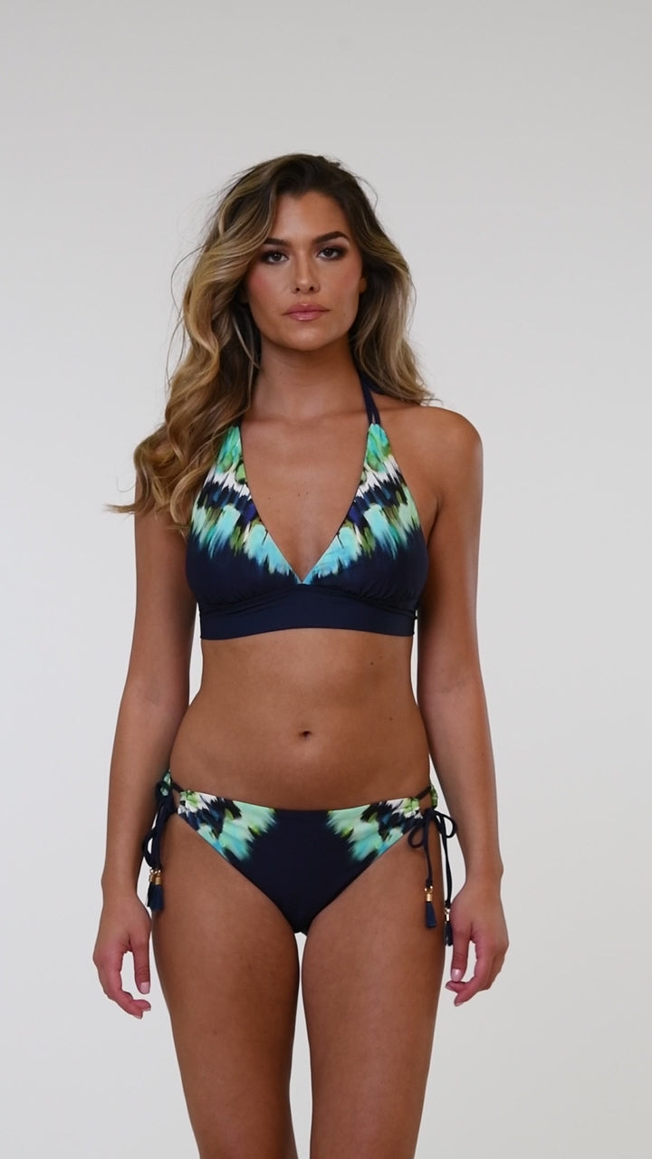 Video of model wearing an indigo and blue tie-dye colored bikini swimsuit bottom featuring a hipster cut and side ties adorned with tassels.