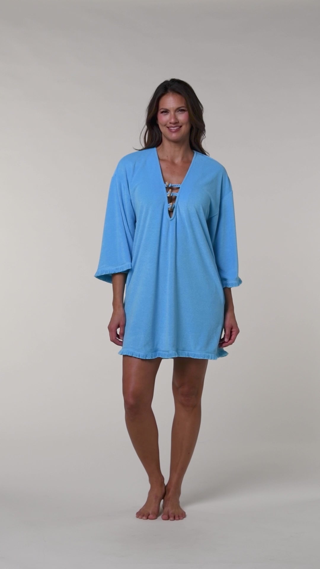 Video of a woman wearing a blue tunic cover up against a white background.