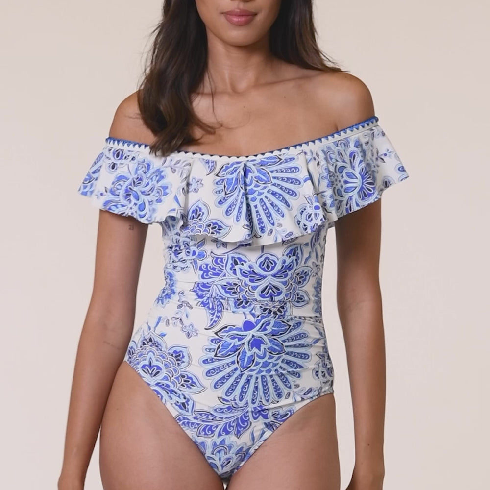 
                  
                    Load and play video in Gallery viewer, Model is wearing an indigo and white multicolored floral printed Off Shoulder Ruffle One Piece
                  
                