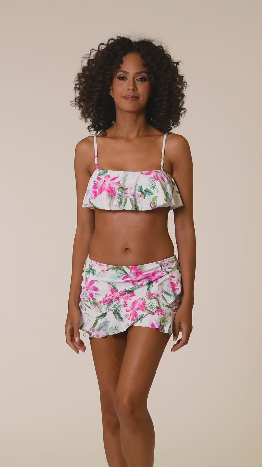 This is a video of a Model is wearing multi colored tropical print on a white backround with this asymmetrical ruffle skirted bottom from our Mystic Palms collection!