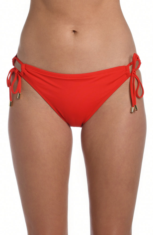 
            
                Load image into Gallery viewer, Model is wearing a cherry colored side-tie hipster swimsuit bottom from our Best-Selling Island Goddess collection.
            
        