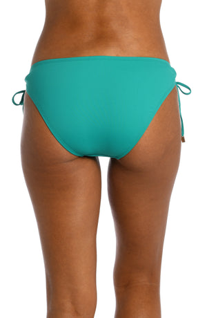 
            
                Load image into Gallery viewer, Model is wearing a emerald colored side-tie hipster swimsuit bottom from our Best-Selling Island Goddess collection.
            
        