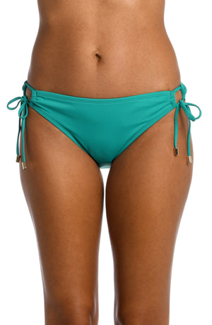 
            
                Load image into Gallery viewer, Model is wearing a emerald colored side-tie hipster swimsuit bottom from our Best-Selling Island Goddess collection.
            
        